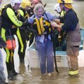 A woman is helped from a boat Monday by local rescuers after she and two others were rescued from th...