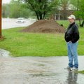 Kevin Sanderlin watches flood waters from his front yard at on Rainbow Road in Rogers on Monday. Rog...