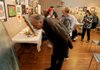 Ken Kvamme looks at some of the paintings guest speaker Barbara Robinson brought to the Artists of Northwest Arkansas club meeting on Thursday at the Arts Center of the Ozarks in Springdale.