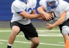  Rogers High quarterback Nick Wary, left, hands off to running back Brandon Blume on Wednesday in Mountie Stadium in Rogers.
