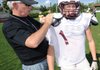 Former longtime Harrison coach Tommy Tice helps Huntsville junior-to-be running back Brandon McRae with his jersey during a May practice at Huntsville High School.