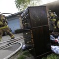 Rogers firefighter Joseph Jerrabeck, left, pulls fire hose from a duplex home Wednesday after knocki...