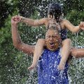 Junior Vega and daughter Laisha, 4, react Wednesday as they are splashed from overhead with a bucket...
