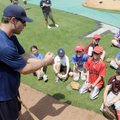 Jamie Romak, left, talks with a group of young players about how to hold a bat during the Northwest ...