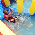 Taveon Mahone, 8, slides into the water on a inflatable water slide Tuesday at Parson Hills Elementa...