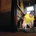 Steven Ribar fills in cracks in a bathroom subfloor Saturday while voluteering with members of Livin...