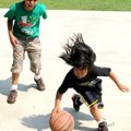 Theo Larky, 9, left, watches as Cade Pere, 10, drives to the basket on Monday in the park at Riordan...