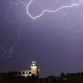 Lightning cuts through a pre-dawn sky Wednesday above the bell tower of Old Main at the University o...