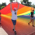  Marchers carry a 50-foot lesbian, gay, bisexual, transgender rainbow banner west on Dickson Street ...