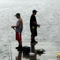 Payton Fitch, 15, left, and Zach Brunetti, 15, weather a soaking shower Tuesday while fishing from a...