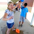 Danny Sierra, 14, right, drops a water balloon as Adrian Penn, 13, reacts to it exploding Wednesday ...