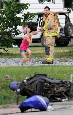 An unidentified woman pleads with Springdale Fireman Cody Keller after emergency personal tried to revive a victim in a motorcycle accident July 7, 2010 on County Line Road in Springdale. Michael Wolf died at the scene.