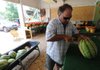  Mike Bonner cuts a watermelon Thursday for customers to sample at his family’s fruit stand in downtown Johnson. Bonner Farm Main Street Market has been in Johnson near the railroad tracks for 11 years. Fayetteville’s northward growth and Springdale’s expansion to the south prompted Johnson to incorporate in 1961. Today, growth in the larger neighboring towns has left Johnson almost surrounded.
