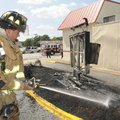Rogers firefighter Kyle Jordan douses the ground Tuesday beneath the drive-up menu sign at Arby’s re...