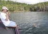 Keith Brashers brings a jumping smallmouth bass to the boat during an early morning trip at Beaver Lake. First light to 10 a.m. is the best window of opportunity for daytime fishing during summer.