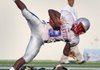 Little Rock Parkview’s Caelon Hardin dives over a Mills defender during Parkviews’ 39-12 victory on Monday at War Memorial Stadium in Little Rock. 
