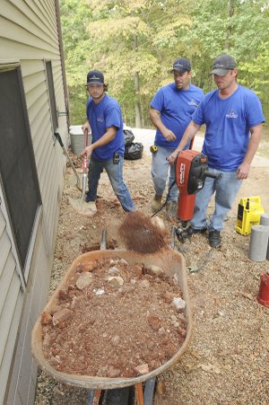 Shane Pullum, from left, Brian Schuchmann and Dennis Hicks work on a foundation at a home in Bella Vista. A wet spring has brought an increase in foundation problems, said Mike Herring, owner of American Standard Foundation Repair.
