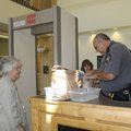 Deputy John Dunn inspects the purses of Betty Watts, left, and Nancy Watts at the entrance of the Be...
