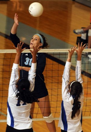 Katie Hugg of Springdale Har-Ber spikes the ball as Rogers Natalie Gutierrez, left, and Katie Pedersen defend Tuesday at Wildcat Arena in Springdale.