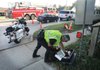 A Fayetteville police officer looks through gear Wednesday as he and others officers investigate a car accident on Joyce Boulevard in Fayetteville where three Street Departments workers were injured. Jo Lynn Jackson, 51, of Fayetteville, driver of the car that hit the workers, faces criminal charges in connection with driving while intoxicated (drugs). The driver of second car that slammed into Jackson’s, Ronnie Davidson, 28, of Springdale, also was arrested in connection with driving while intoxicated.