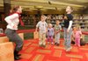 Suzanne Cox, left, Children’s Library staff member, leads a Storytime session Tuesday about stretching and exercise at Bentonville Public Library. From the left are Cox, Monty Eskew, 4, Madelyn Eskew, 3, Joseph Navarrete, 4, Jacob Hupp, 10, Emily Ensor and her daughter Emma Ensor, 2. The 6:30 p.m. Tuesday reading program is one of three new Storytime program times.
