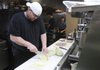 Chef Rob Nelson cuts cabbage Thursday at Tusk & Trotter American Brasserie in downtown Bentonville while preparing a special menu for today’s First Friday Oktoberfest event. The restaurant, along with other vendors, will be offering bratwurst and other foods for the event.

