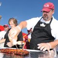 TAILGATE TREAT Hog Tide Bar-B-Que team members Will Willis, right, and DeElla Neyer wrap ribs Saturd...