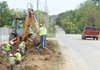A pickup travels east on Cato Springs Road in Fayetteville as workers with Dean Crowder Construction of Bentonville install a utility line as part of improvements along the roadway.
