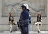 A Greek riot policeman watches anti-government protesters Thursday in Athens during a changing of the presidential guard, known as Evzones, at the Tomb of the Unknown Soldier.
