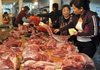 A woman selects meat at a market Friday in Fuyang in central China, where food inflation has remained steady at 13.4 percent since August. 