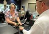 Sandy Hollomon, a teller at Arvest Bank, counts out cash for customer Scott Short on Wednesday at the branch on Joyce Avenue in Fayetteville. The branch is one of the busiest for the bank.