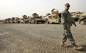 A U.S. army soldier walks past military Humvees ready to be shipped out of Iraq at a staging yard at Camp Sathe on Saturday, Oct. 15, 2011. 