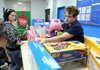 Jainie Hays, left, watches as Kathy Ryan, customer service associate with Walmart, scans items Hays is putting on layaway Wednesday at the Walmart on Pleasant Grove Road in Rogers. Hays said she is happy she has the layaway option because this will allow her to give her children a bigger Christmas this year.
