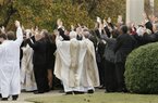 Mourners and clergy raise their hands as they call the Hogs, the University of Arkansas Razorback cheer, after the funeral of tight end Garrett Uekman at Christ the King Catholic Church in Little Rock, Ark., Monday, Nov. 28, 2011. Uekman died Nov. 20 from an undiagnosed heart condition. He was 19. (AP Photo/Danny Johnston)