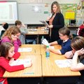 Jill Law, center, helps her sixth-graders as they read aloud about the Panama Canal on Friday at Hel...