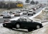 Traffic passes slowly Tuesday past a car abandoned in a ditch alongside the northbound lanes of Bloomington Street (U.S. 71 Business) in Lowell. Overnight snowfall totals from a dusting to more than inch fell in Northwest Arkansas leaving roadways slick during the morning commute.