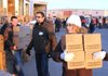 Jennifer Muro, a Walmart employee, helps carry products to pallets Friday ready to be distributed to drive-through recipients at Sharing and Caring of Benton County at the Benton County Fairgrounds in Bentonville. Sharing and Caring predicted handing out gifts to more than 1,900 families.
