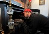 Kevin Mansell inspects and cleans the fire box of a wood stove in a Springdale home on Wednesday.
