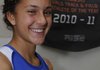 Maggie Montoya smiles Dec. 9 while standing in front of the banner that names her the Gatorade Arkansas Girls Track and Field Athlete of the Year at the Rogers High School fieldhouse.