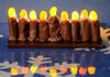 Creating an edible menorah requires chocolate frosting, Tootsie Rolls and orange and yellow jelly beans.
