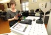 Carlye Dennis, library associate at the Fayetteville Public Library, shows on Friday the three types of electronic book readers available to library patrons for checkout at the library’s circulation desk.