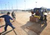 Mike Thompson, a representative for Easton Sod Farm in Bixby, Okla., operates a skid-steer loader Wednesday. Thompson was working with Federico Juarez, from left, Arturo Saucedo and Antonio Cervantez to lay Patriot Bermuda sod on a playing field in the Farmington Sports Complex at 323 S. Southwinds Road in Farmington.
