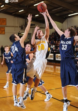 Prairie Grove’s Marcus Patterson, center, leaps to score in the lane as Shiloh Christian’s Darian Harris, right, and Kyle Veit reach to block Tuesday during the first half of play in Prairie Grove.