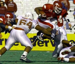 Arkansas running back Cedric Cobbs jumps over Texas defenders Casey Hampton (64) and Montrell Flowers in the 2000 Cotton Bowl, a 27-6 Razorbacks’ victory.