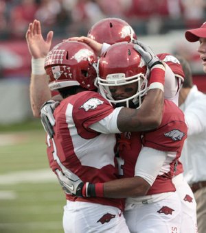 Arkansas Razorbacks receivers Joe Adams (left) and Jarius Wright celebrate on the sidelines after Adams scored during a game against Mississippi State earlier this season. Adams is second on the Razorbacks’ career receptions list, just six catches behind Wright.