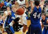 Tony Dennis, Springdale High senior, leaps around Rogers High senior Nathan Musso, right, while driving to the basket during the first half Friday at Bulldog Gym in Springdale.
