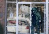 A member of the Bentonville Bomb Squad leaves the Arvest Bank, Monday Jan, 9, 2012, in Fayetteville after the police and the squad were called out to the bank were a woman reported she had been kidnapped and a bomb strapped to her ankle. She had been lead out earlier after the suspected device looked to have been removed.