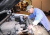 Lonnie Phelps of Benton County’s Road Department checks the engine fluid levels Friday of a county-owned 2011 Silverado pickup at department headquarters in Bentonville. County Judge Bob Clinard is seeking to have part of the county’s fleet converted to use compressed natural gas.
