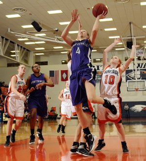 Fayetteville’s Aubrey Edie, center, takes the ball to the basket in front of Rogers Heritage’s Raya Jones during their game Friday in Rogers.
