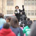 Marta Collier leads chants with a bullhorn as a large crowd marches up West Dickson Street while par...